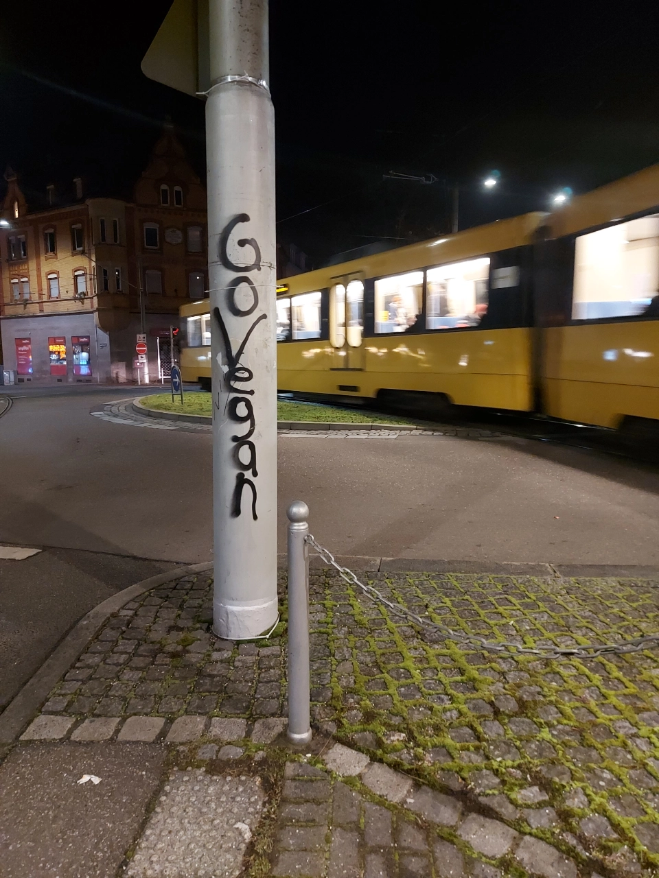 a pole in stuttgart's ostendplatz, where someone sprayed “go vegan” on it. in the back the u4 heading to untertürkheim can be seen.